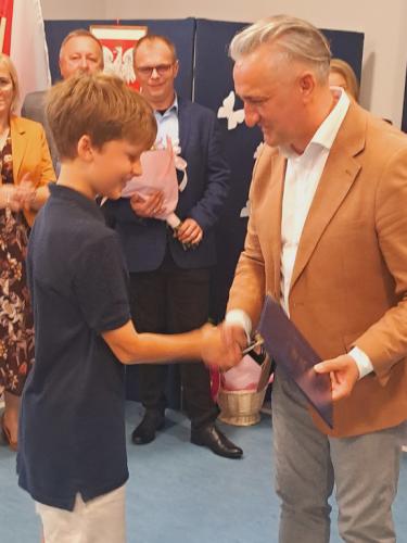 Wójt Gminy Łączna wręcza stypendium uczeniowi klasy 4 Mikołajowi Domoradzkiemu.