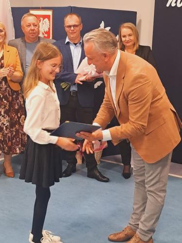 Wójt Gminy Łączna wręcza stypendium uczennicy klasy 4 Lenie Rejek.